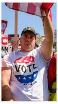 a man holding up a t - shirt that says vote